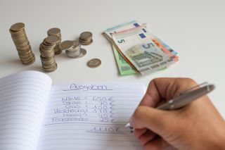 Foto: Person schreibt in Haushaltsbuch